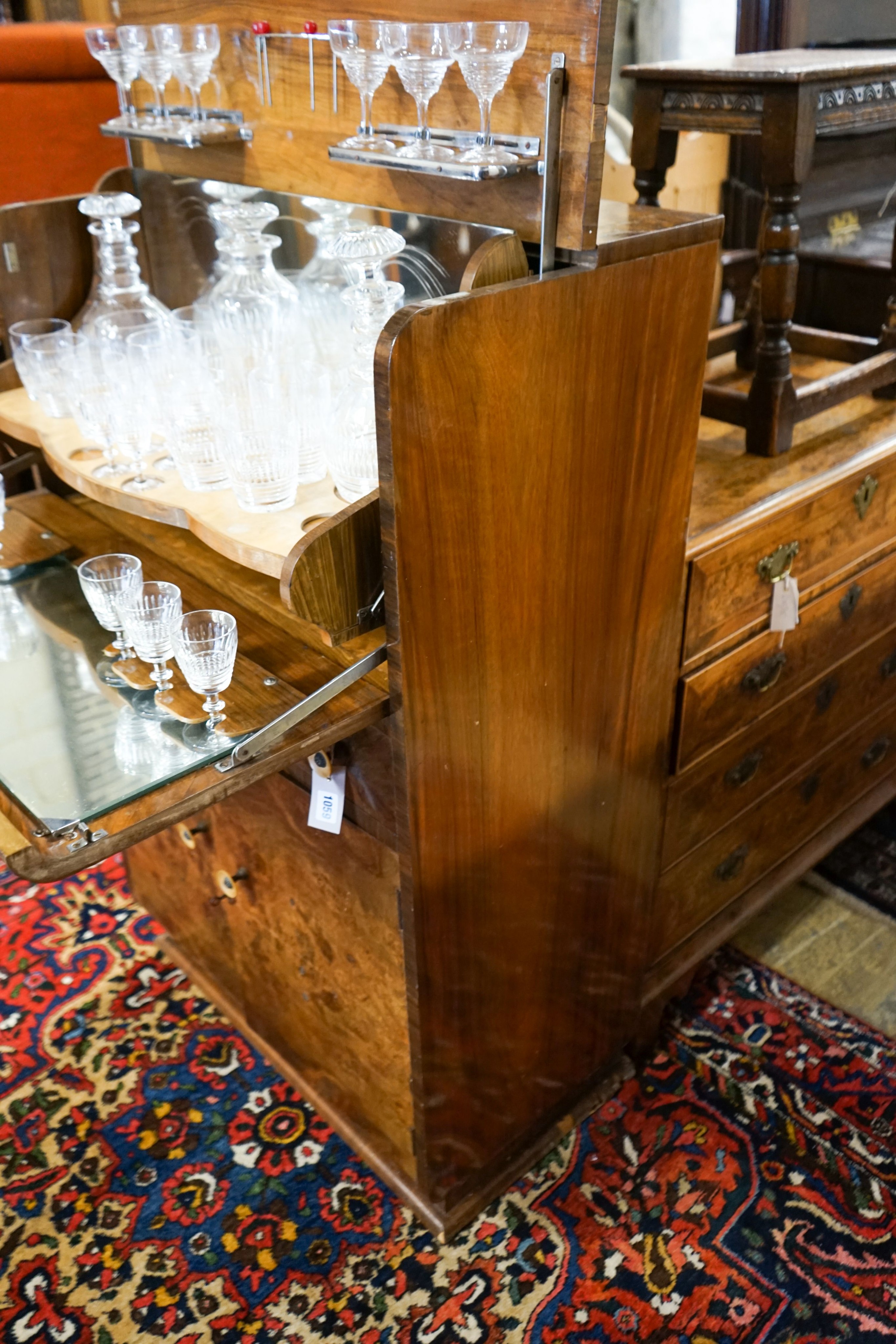 An Art Deco figured walnut and maple-lined cocktail cabinet, width 74cm, depth 41cm, height 121cm, containing a part suite of cut crystal table glass